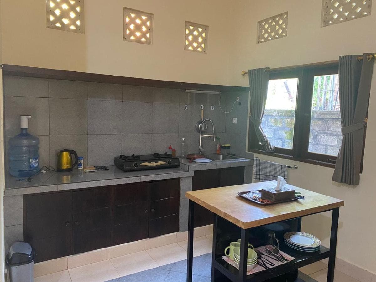 a kitchen with a counter and a table in it at Sekar Waru Homestay in Sanur
