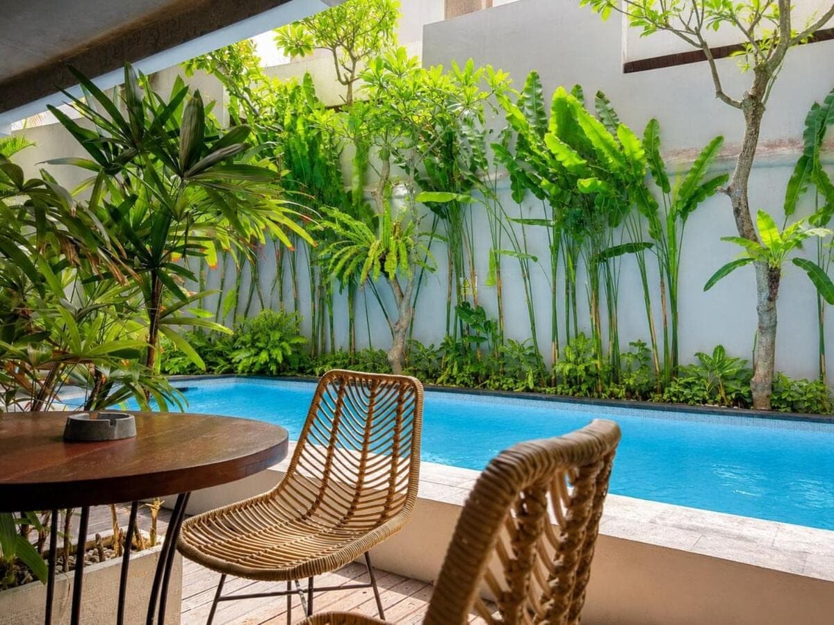 a patio with a table and chairs and a swimming pool at Balissimo - 1BR Pool View Studio Seminyak in Seminyak