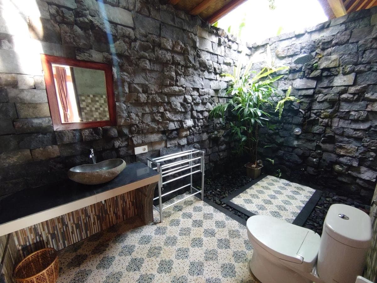 a stone bathroom with a sink and a toilet at Abian view house in Sidemen