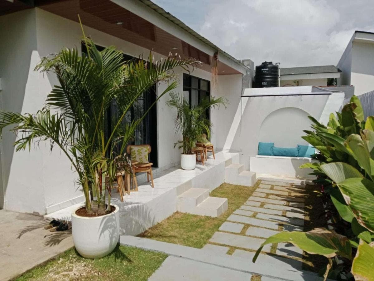a house with a garden with palm trees and stairs at Yuli Homestay in Uluwatu
