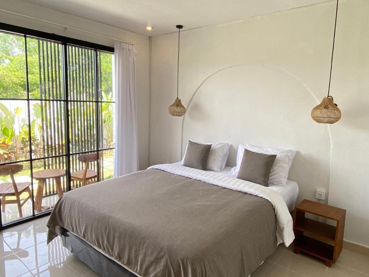 a bedroom with a large bed and a large window at Yuli Homestay in Uluwatu