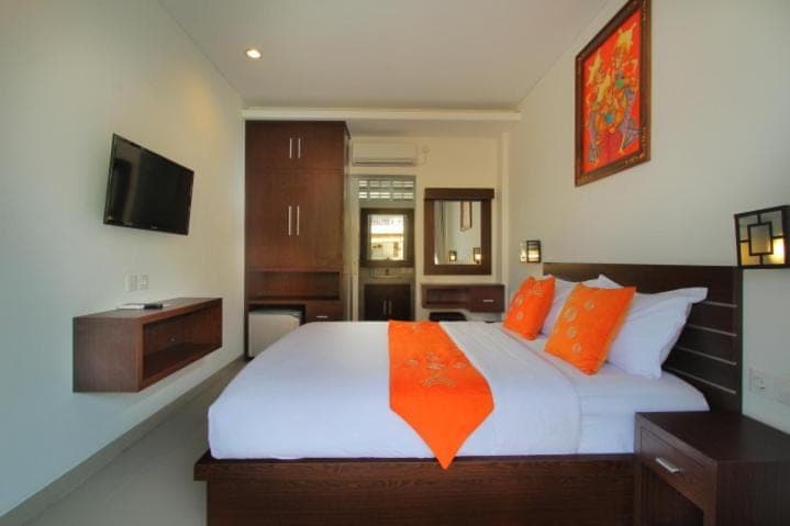a bedroom with a large white bed with orange pillows at Lotus Tirta Seminyak in Seminyak
