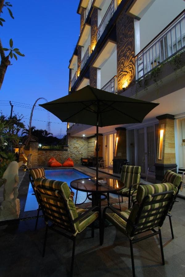 a patio with a table and chairs and an umbrella at Lotus Tirta Seminyak in Seminyak
