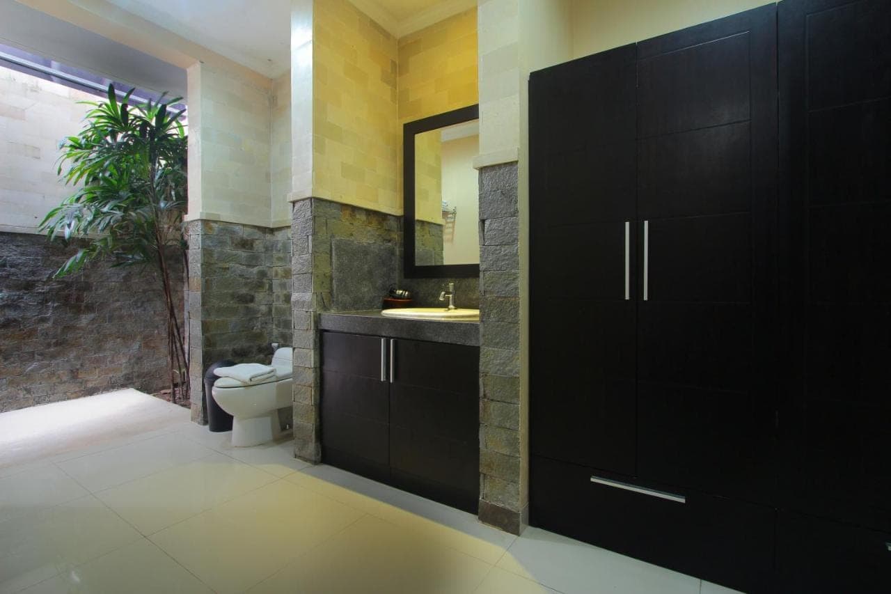 a bathroom with a toilet and a sink and a mirror at Lotus Tirta Seminyak in Seminyak