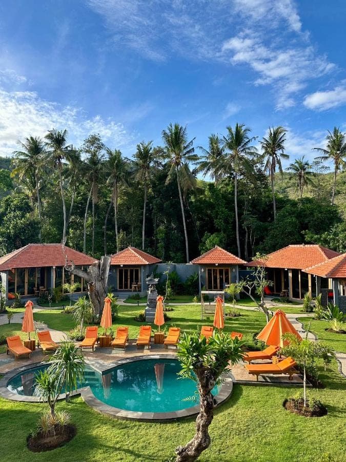 a resort with a pool and chairs and palm trees at Aqua Dive resort Amed in Amed