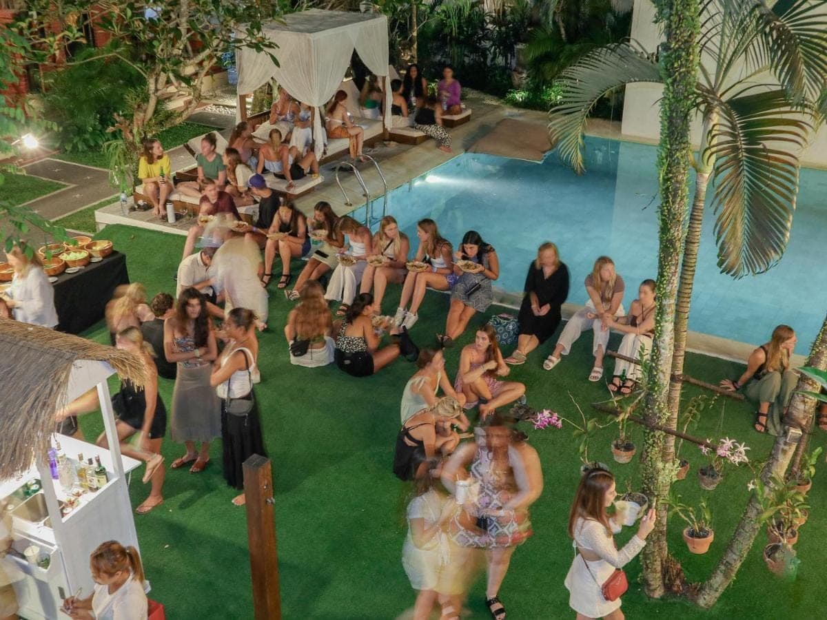 a group of people sitting around a swimming pool at Puri Garden Hotel &amp; Hostel in Ubud