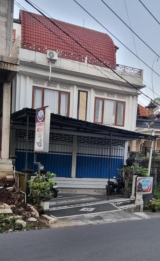 a white building with a red roof and a street at Sri Sedana Homestay in Sidemen