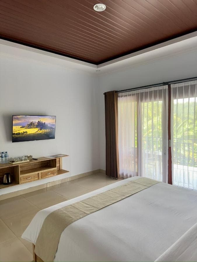 a bedroom with a large bed and a large window at D'Kusuma House Sidemen in Sidemen