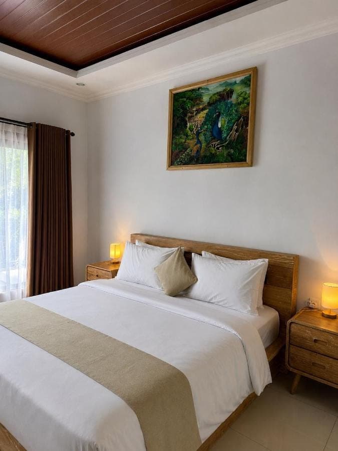a bedroom with a white bed and a painting on the wall at D'Kusuma House Sidemen in Sidemen