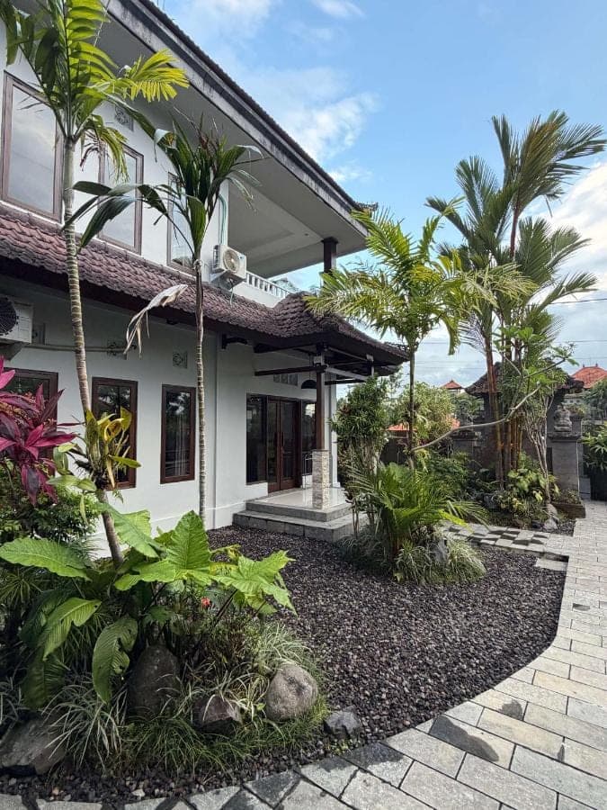 a house with palm trees in front of it at Anugrah Rice Field House in Ubud