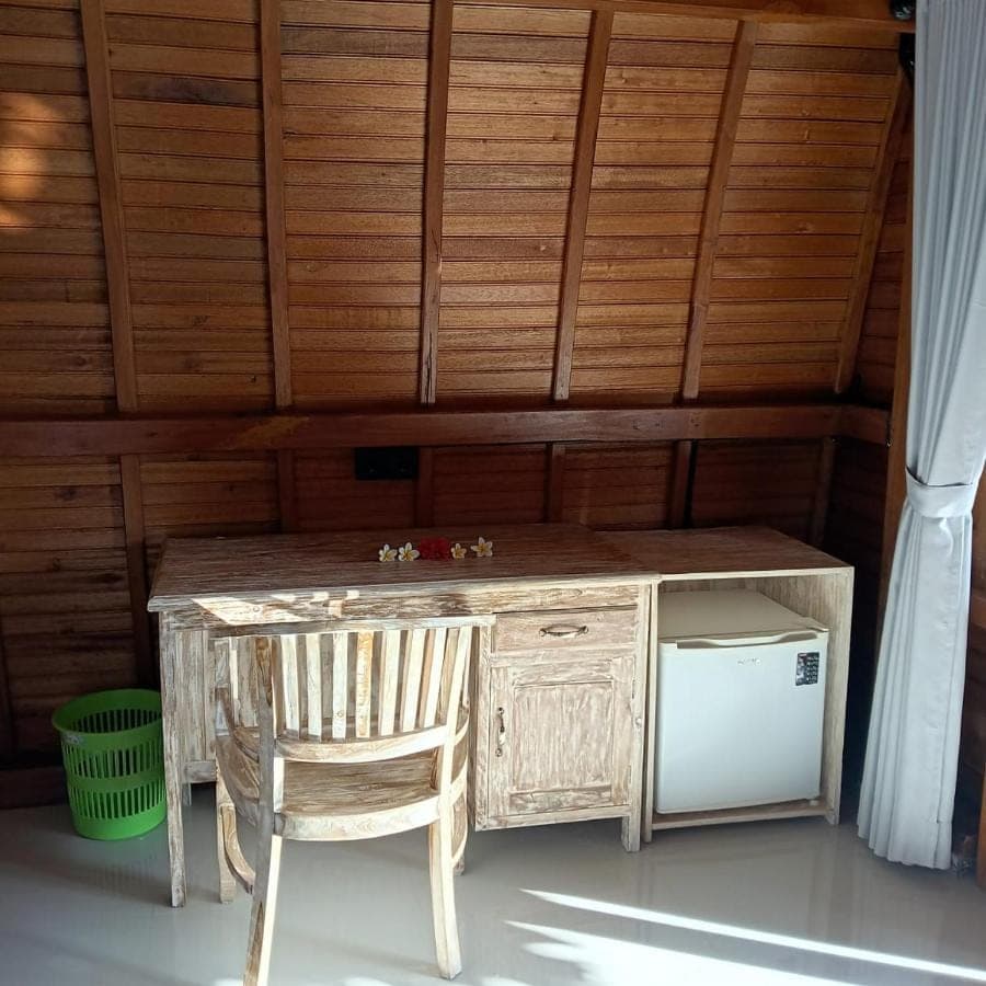 a wooden desk and a chair in a room at Agung Inn Amed in Amed