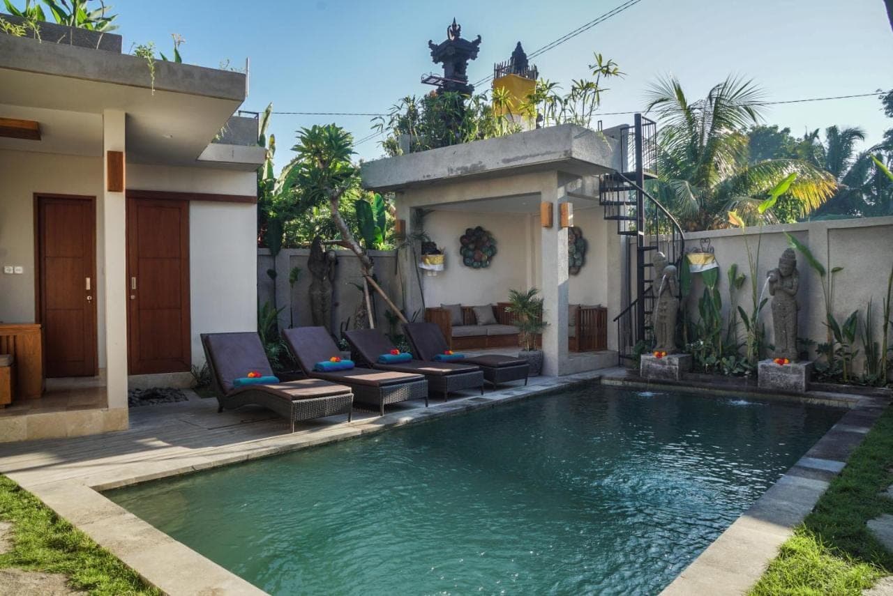 a swimming pool with chairs and a house at Bisma Terrace Suite Ubud in Ubud