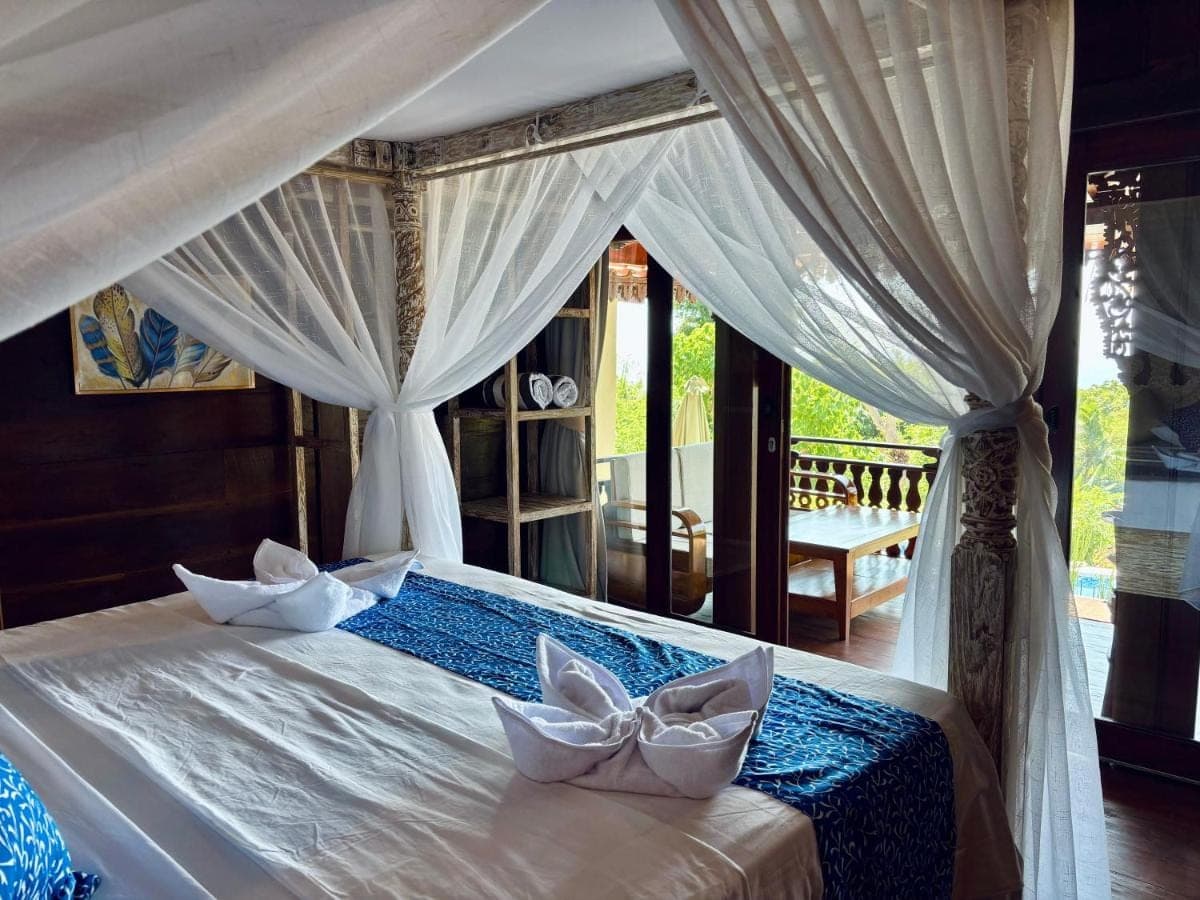 a bedroom with a bed with white drapes at The Atlas Villas in Amed
