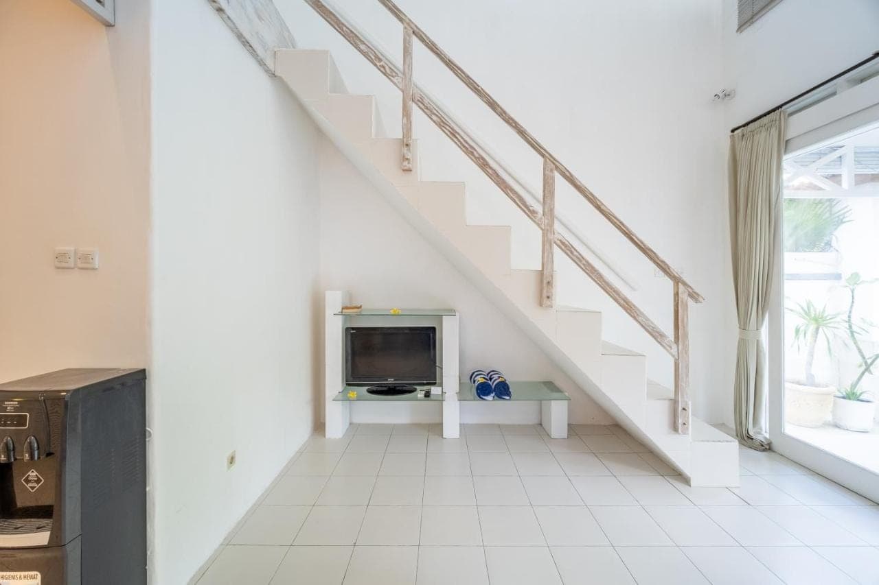 a living room with a staircase and a tv at Villa Margaretta in Seminyak