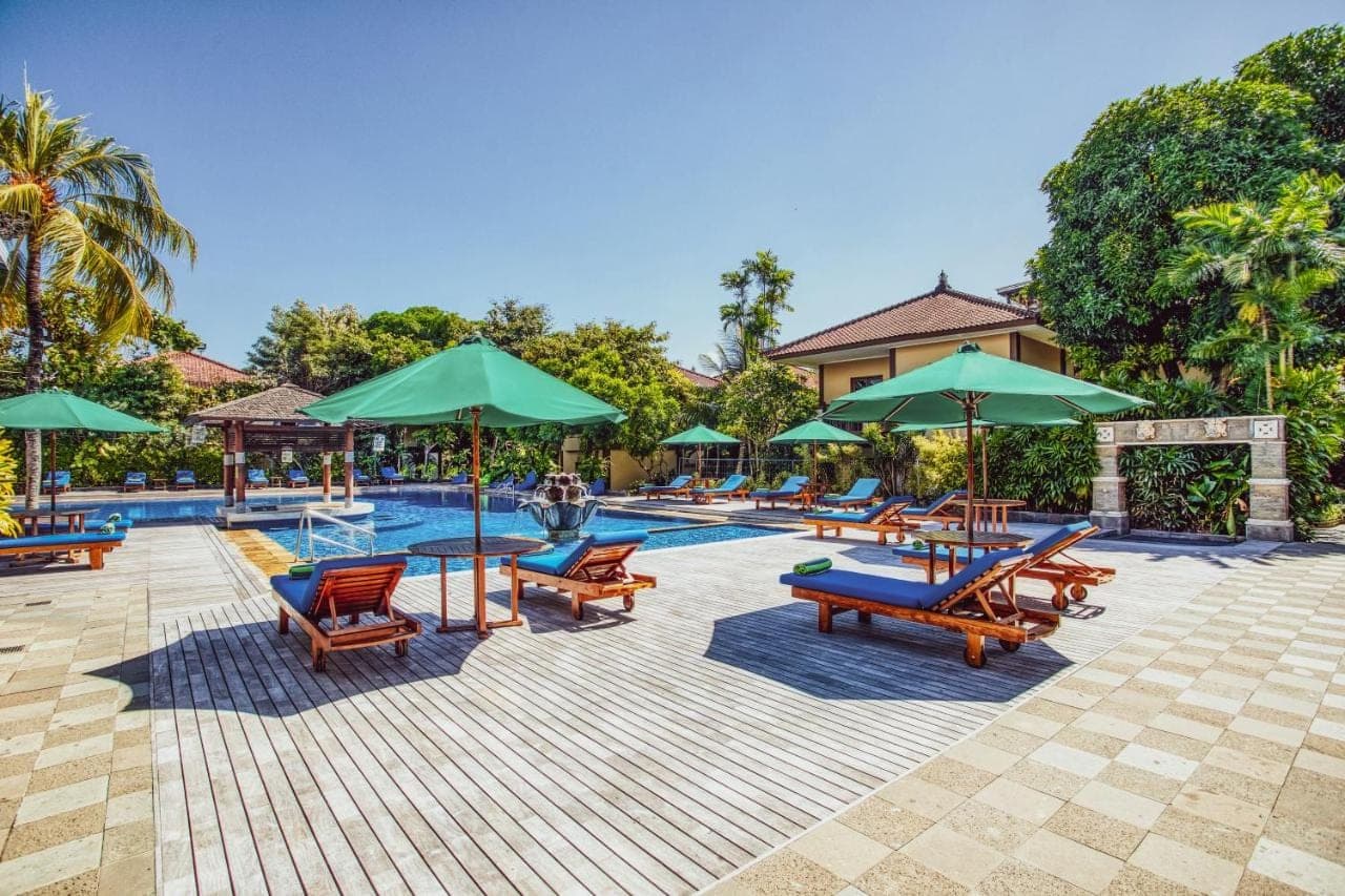 a pool with a bunch of chairs and umbrellas at Risata Bali Resort &amp; Spa in Kuta