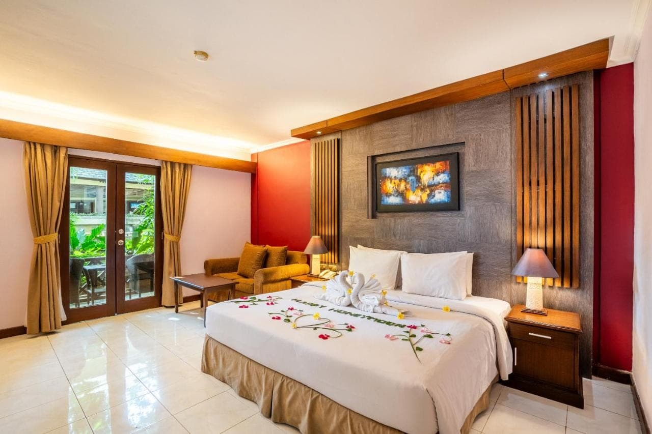 a hotel room with a large bed with flowers on it at Risata Bali Resort &amp; Spa in Kuta