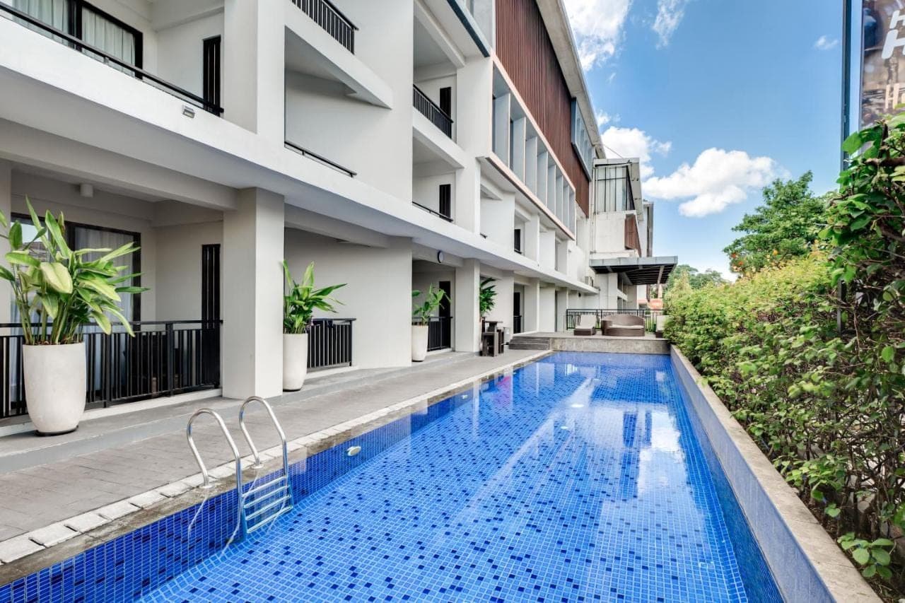 a swimming pool in front of a building at HARRIS Hotel Seminyak in Seminyak