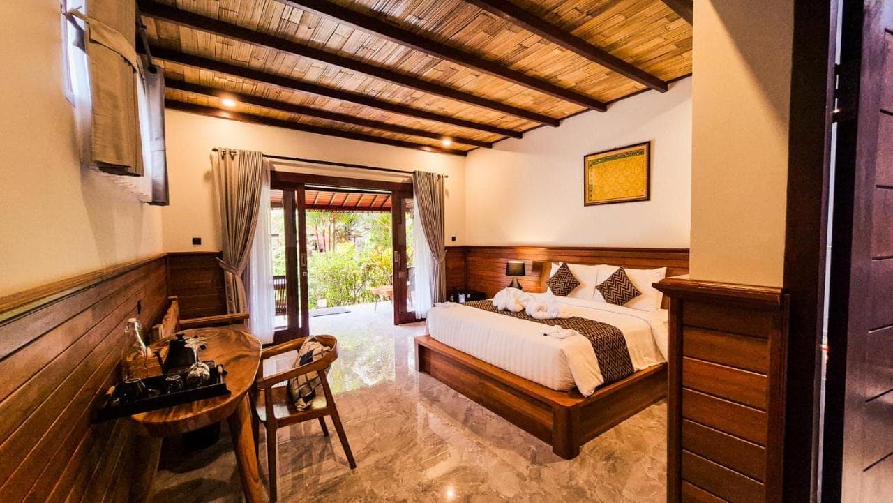 a bedroom with a bed and a table and a desk at Griya Valud in Sidemen