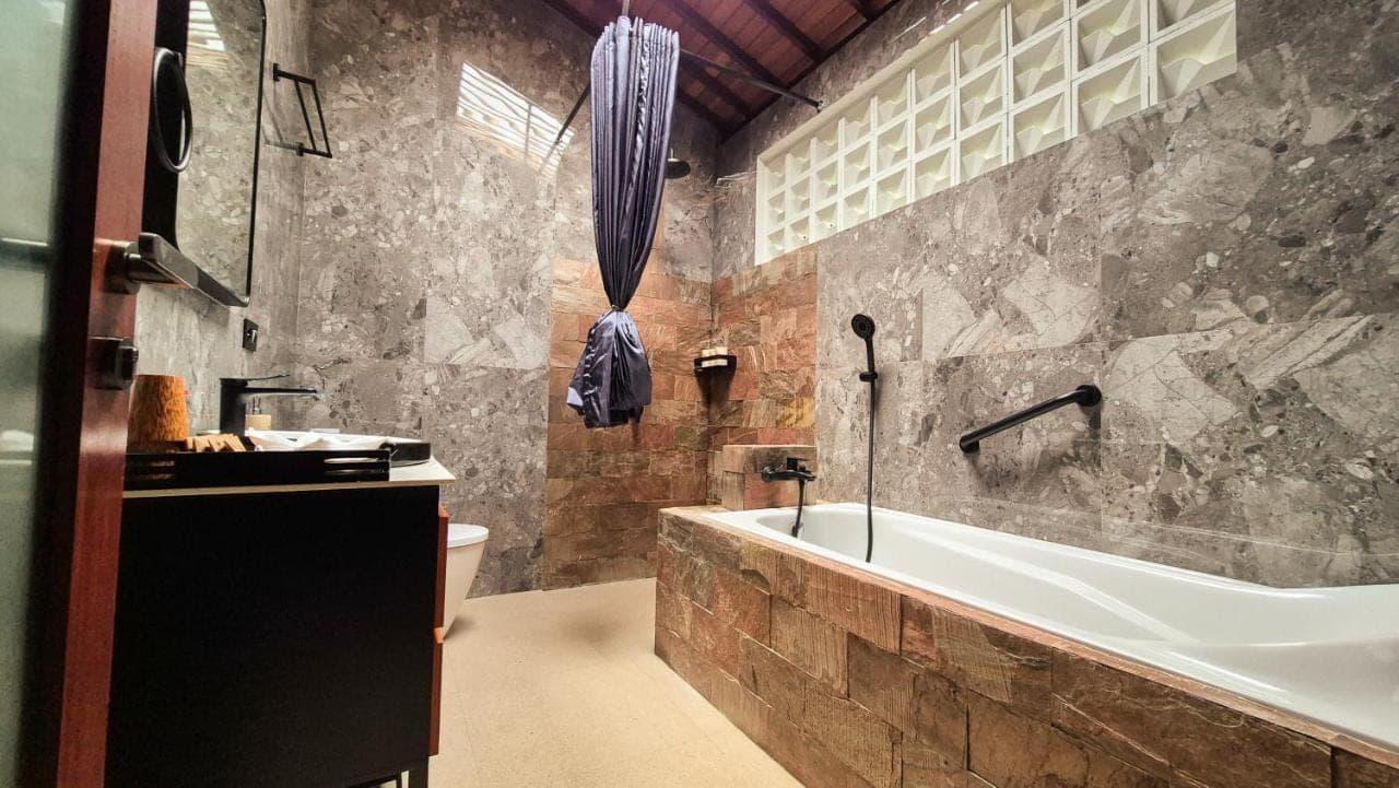 a bathroom with a bath tub and a toilet at Griya Valud in Sidemen