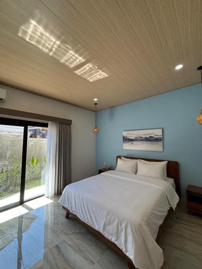 a bedroom with a large white bed and a window at Sora House in Nusa Dua