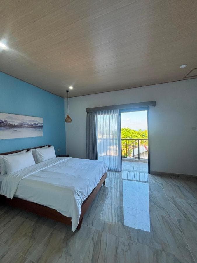 a bedroom with a large bed and a large window at Sora House in Nusa Dua