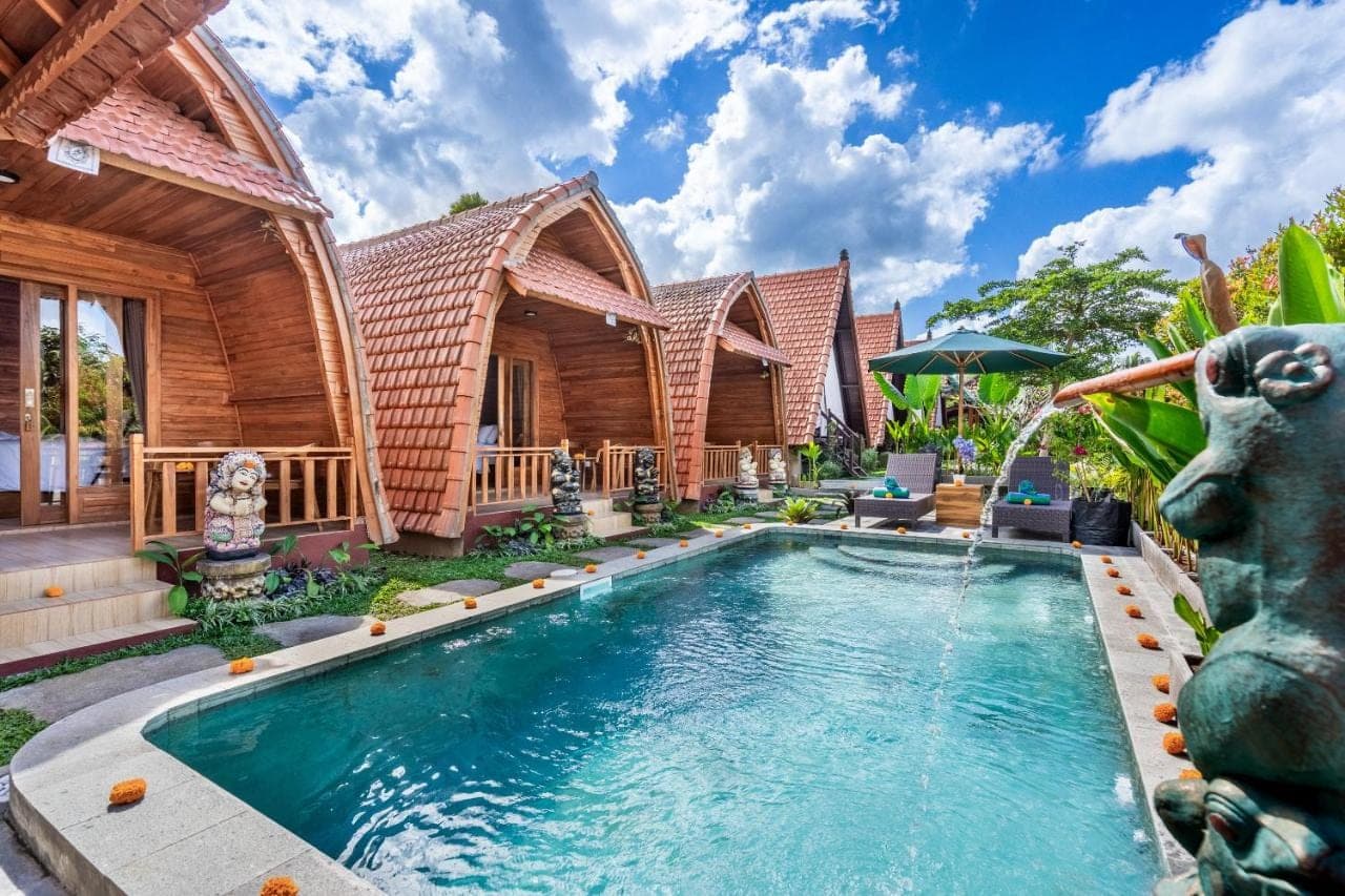 a home with a swimming pool in front of a house at Lumbung Sari villa ubud by Dewanta Property in Ubud