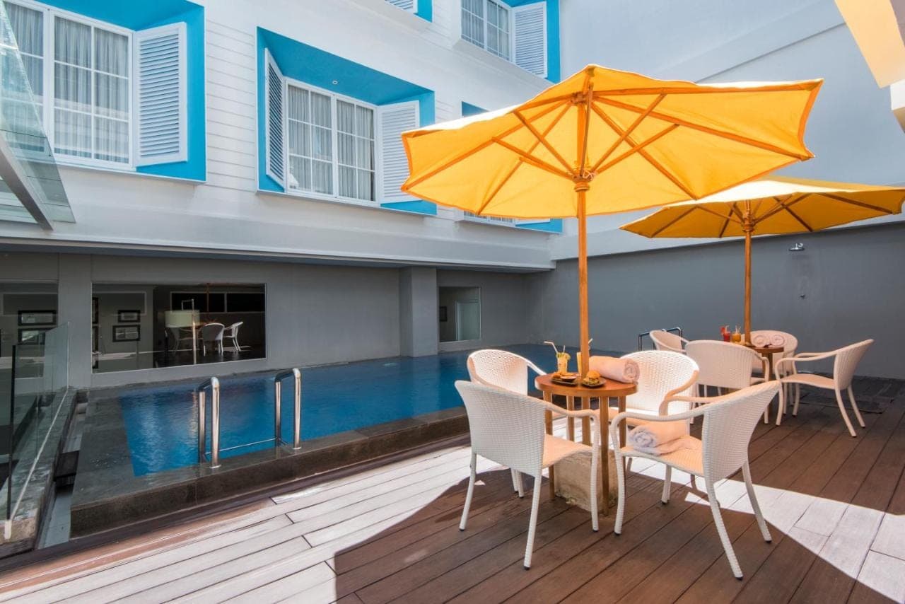 a patio with a table and two umbrellas at Yan's House Hotel in Kuta
