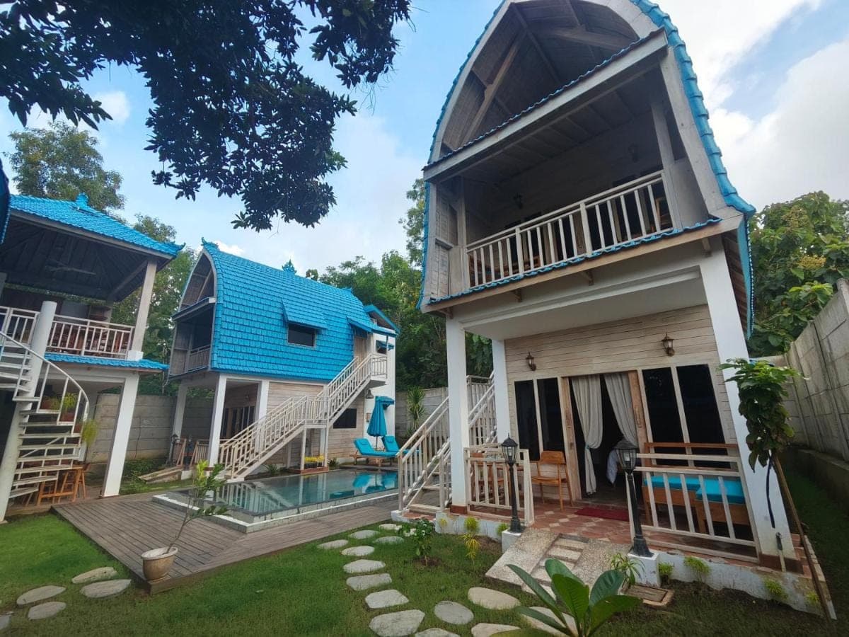 a house with a blue roof and a yard at Nanun Paradise Uluwatu in Uluwatu