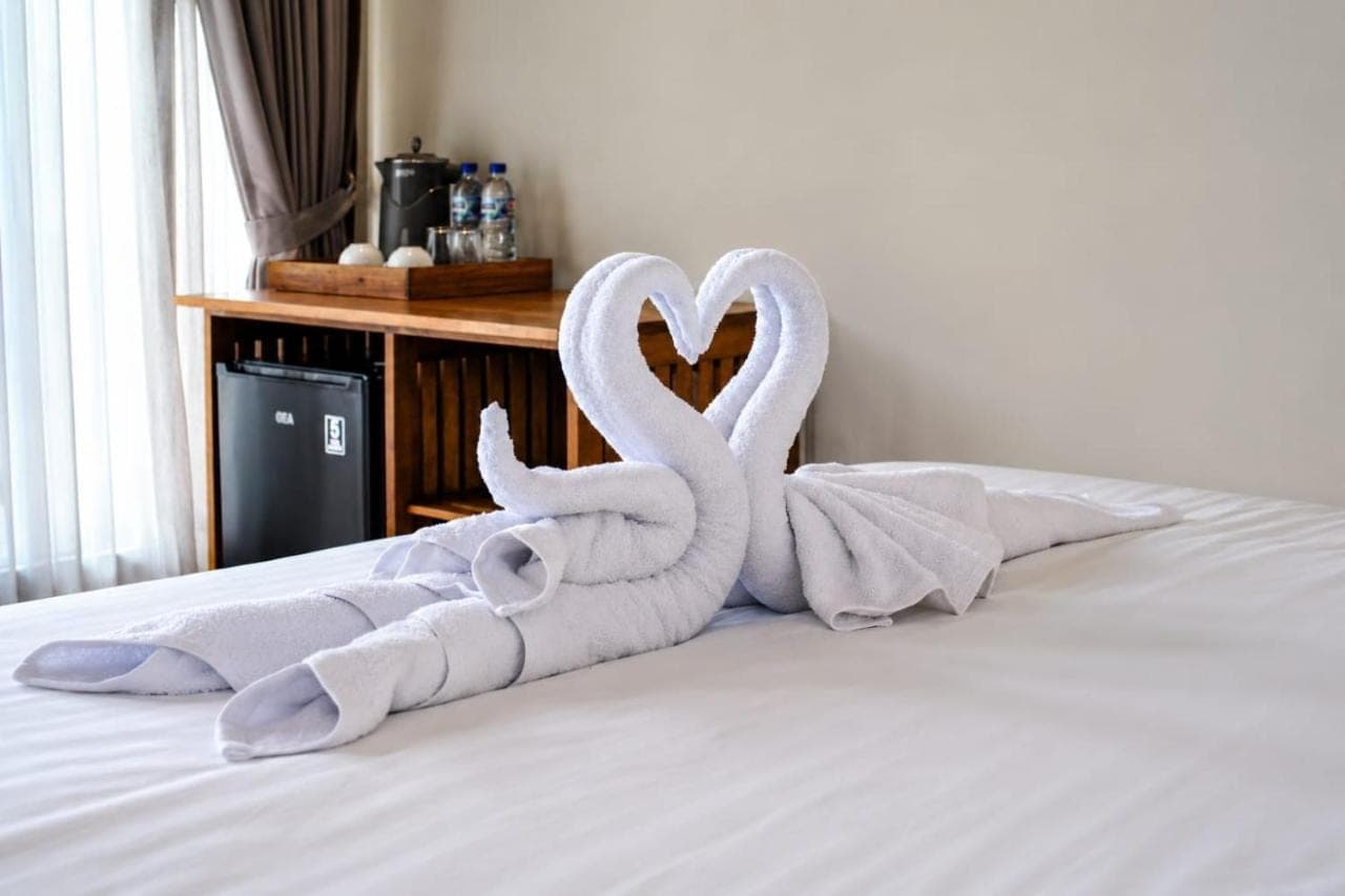 two towel swans are sitting on a bed at SARALA sidemen in Sidemen
