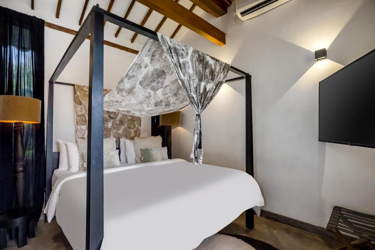 a bedroom with a white bed and a tv at Bloom Resort Bali by BaliSuperHost in Canggu