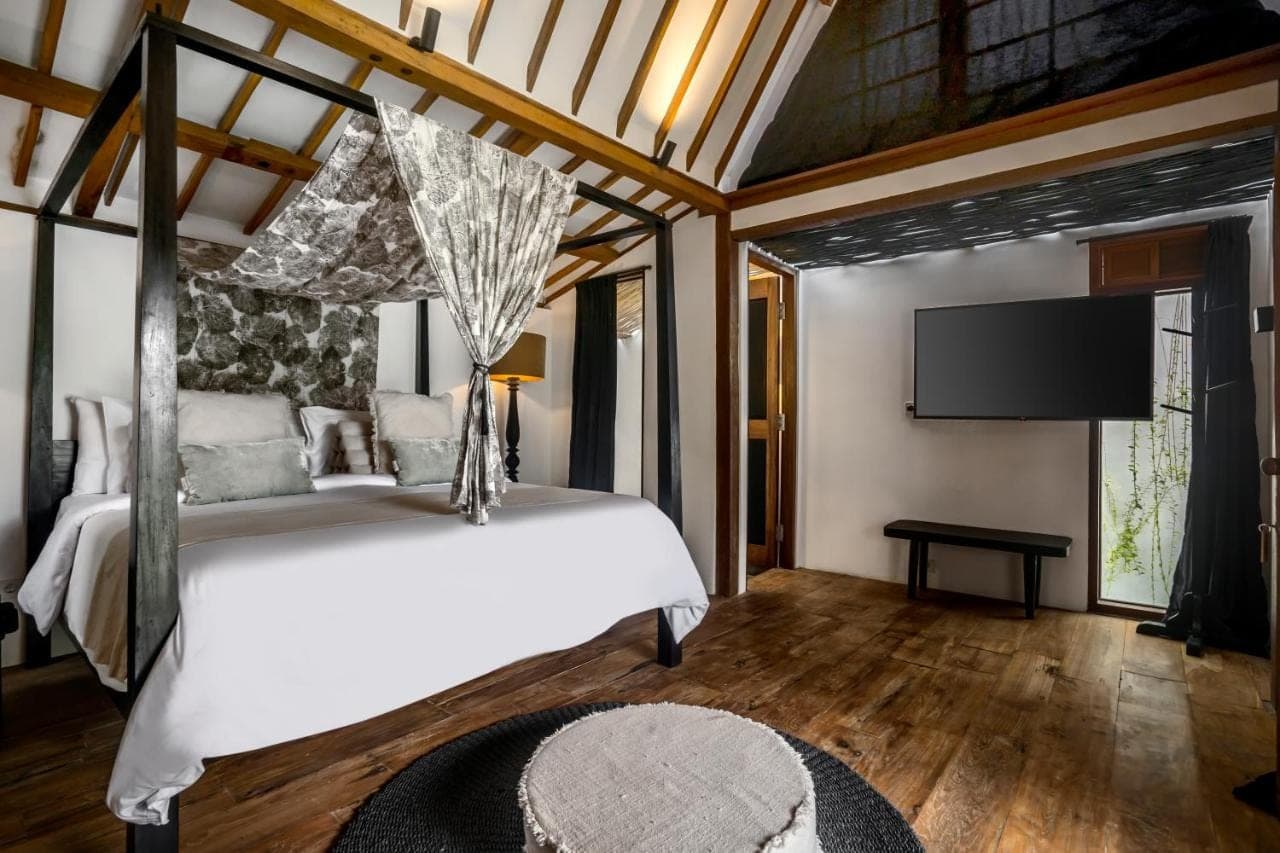 a bedroom with a bed and a flat screen tv at Bloom Resort Bali by BaliSuperHost in Canggu