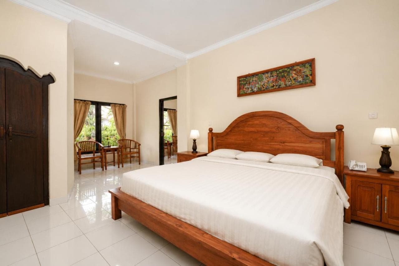 a bedroom with a large bed and a dining room at Swastika Bungalows in Sanur