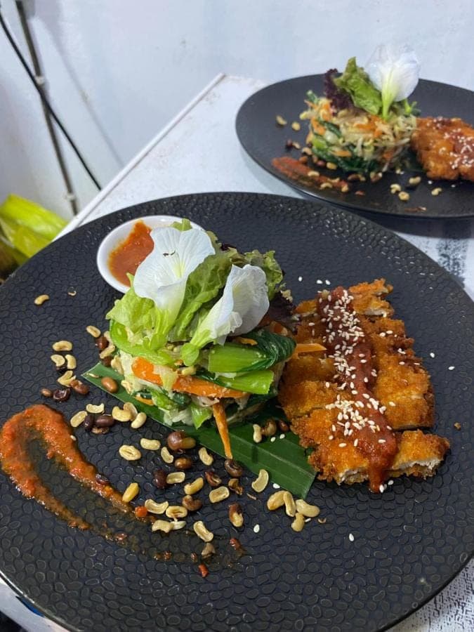 two black plates with food on a table at Adisamasta Guesthouse in Sidemen