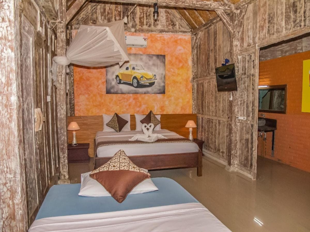 a bedroom with two beds and a tv and a car painting at Griya Pasir Ukir in Sanur
