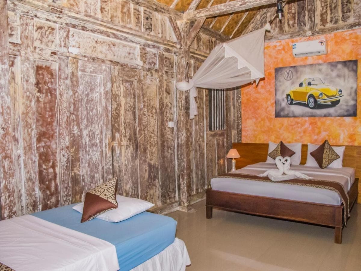 a bedroom with two beds and a painting of a car at Griya Pasir Ukir in Sanur