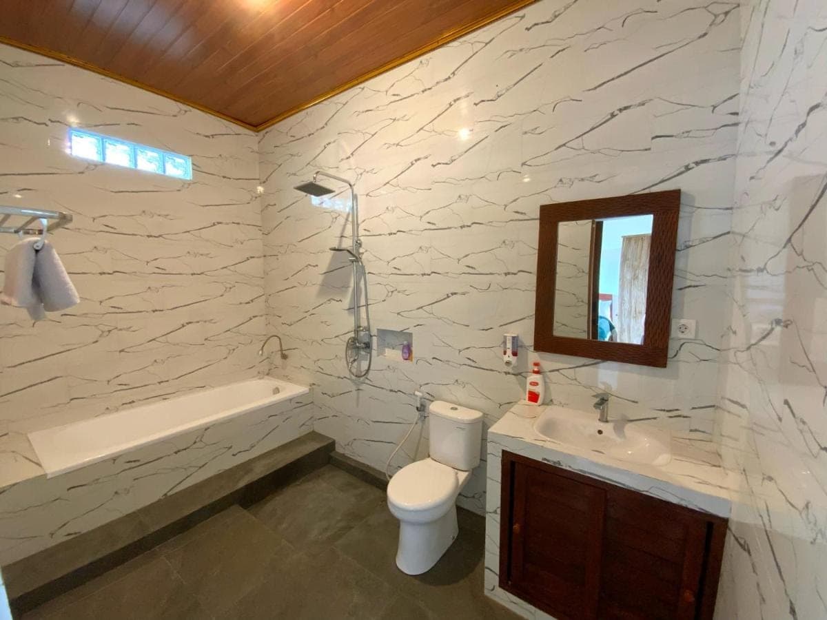 a bathroom with a toilet and a sink and a mirror at Rumah Bagus Jayanti in Sidemen