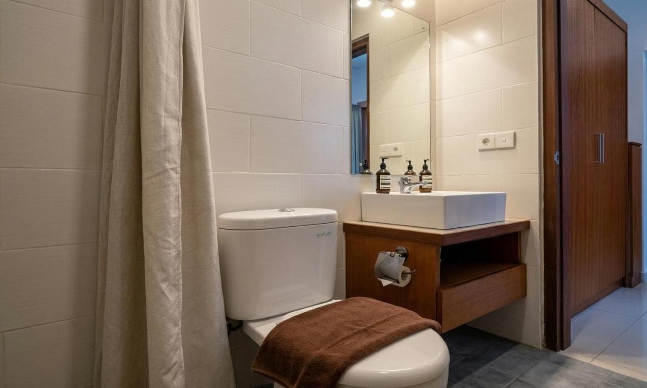 a bathroom with a toilet and a sink and a mirror at Cening Ayu Sanur in Sanur