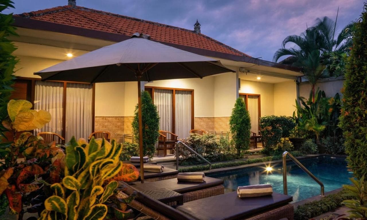 a house with an umbrella and a swimming pool at Cening Ayu Sanur in Sanur