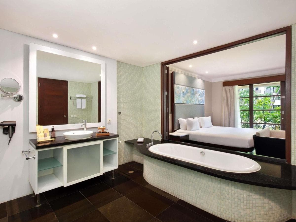 a bathroom with a large mirror and a bed and a tub at Novotel Bali Nusa Dua in Nusa Dua