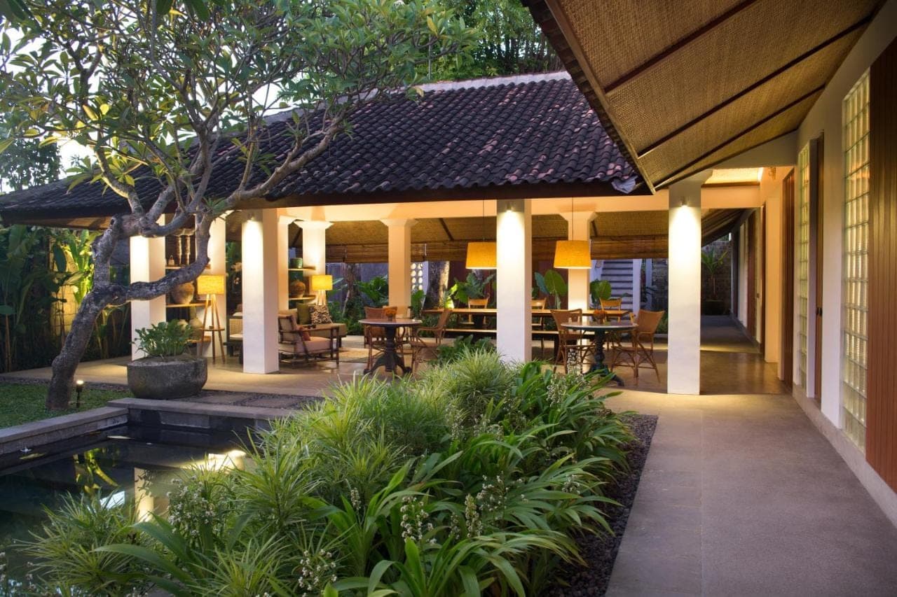 an outdoor patio with tables and chairs and a pond at Atelier TE Designer Guesthouse in Sanur