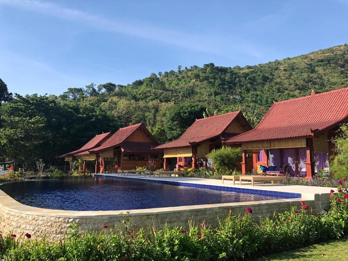 a resort with a swimming pool in front of buildings at Good Karma Bungalows in Amed