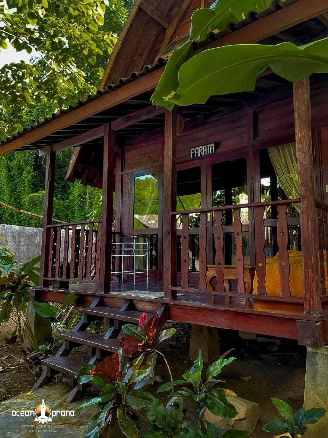 a wooden porch on a house with stairs at Ocean Prana Village in Amed