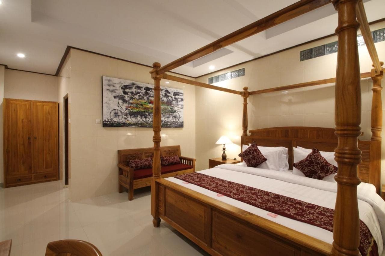 a bedroom with a four poster bed and a couch at Yuni's House in Ubud