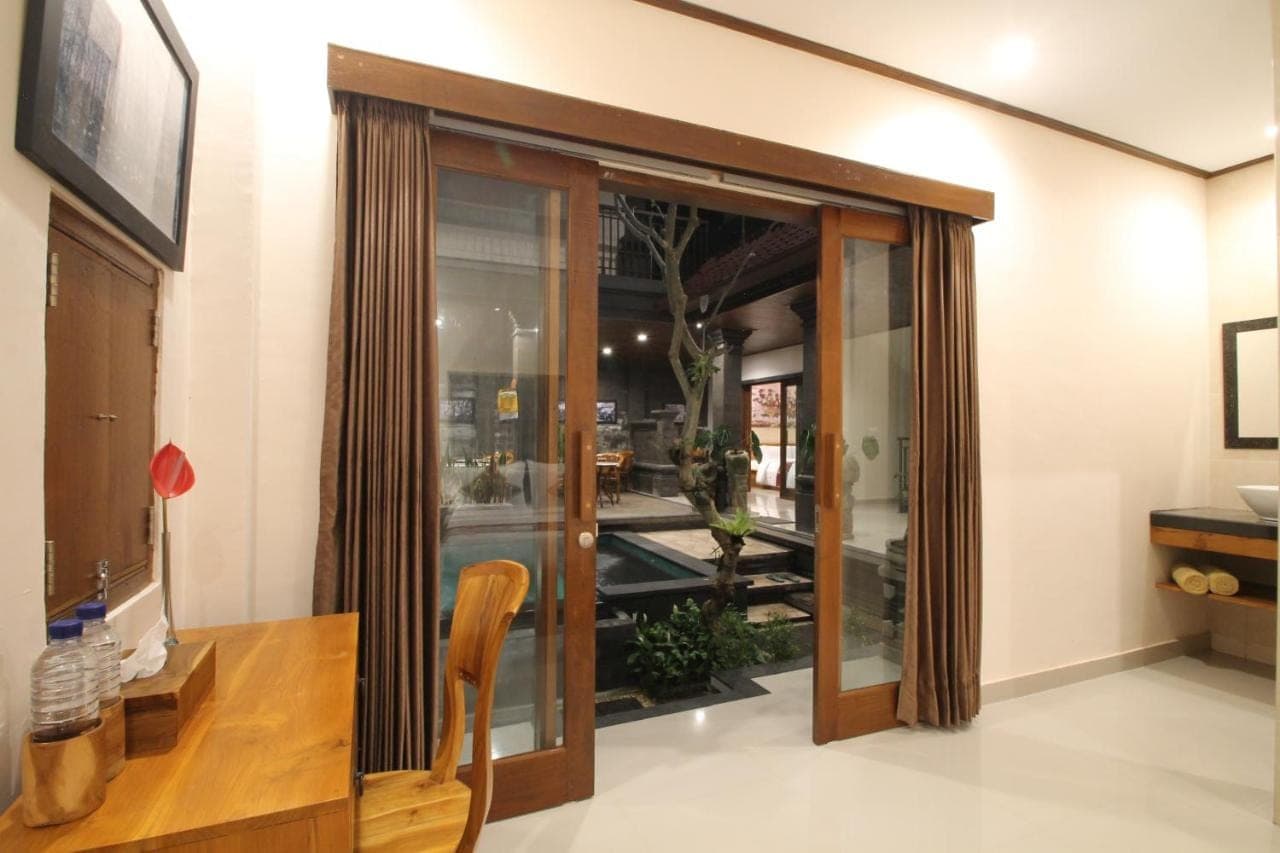 a room with sliding glass doors and a wooden chair at Yuni's House in Ubud
