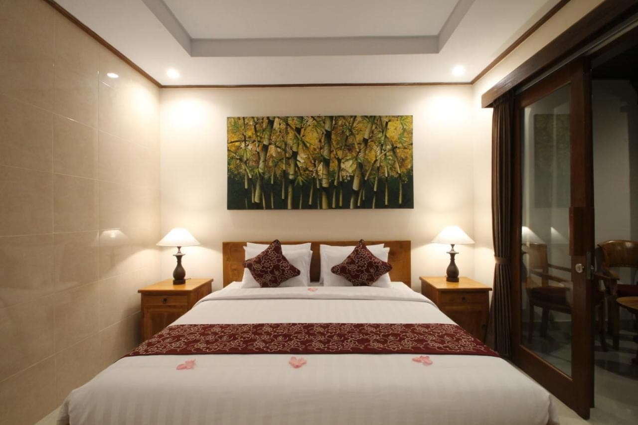 a bedroom with a bed and a painting on the wall at Yuni's House in Ubud