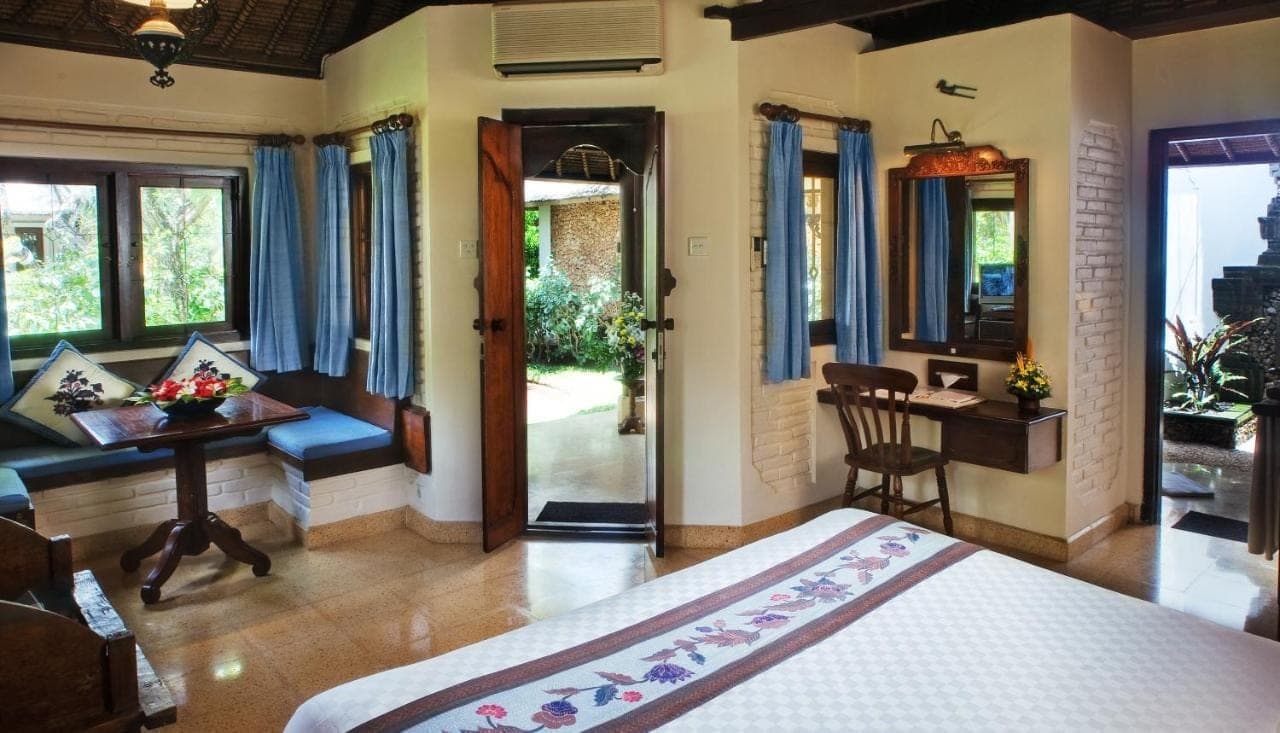 a bedroom with a bed and a desk and a table at Poppies Bali in Kuta