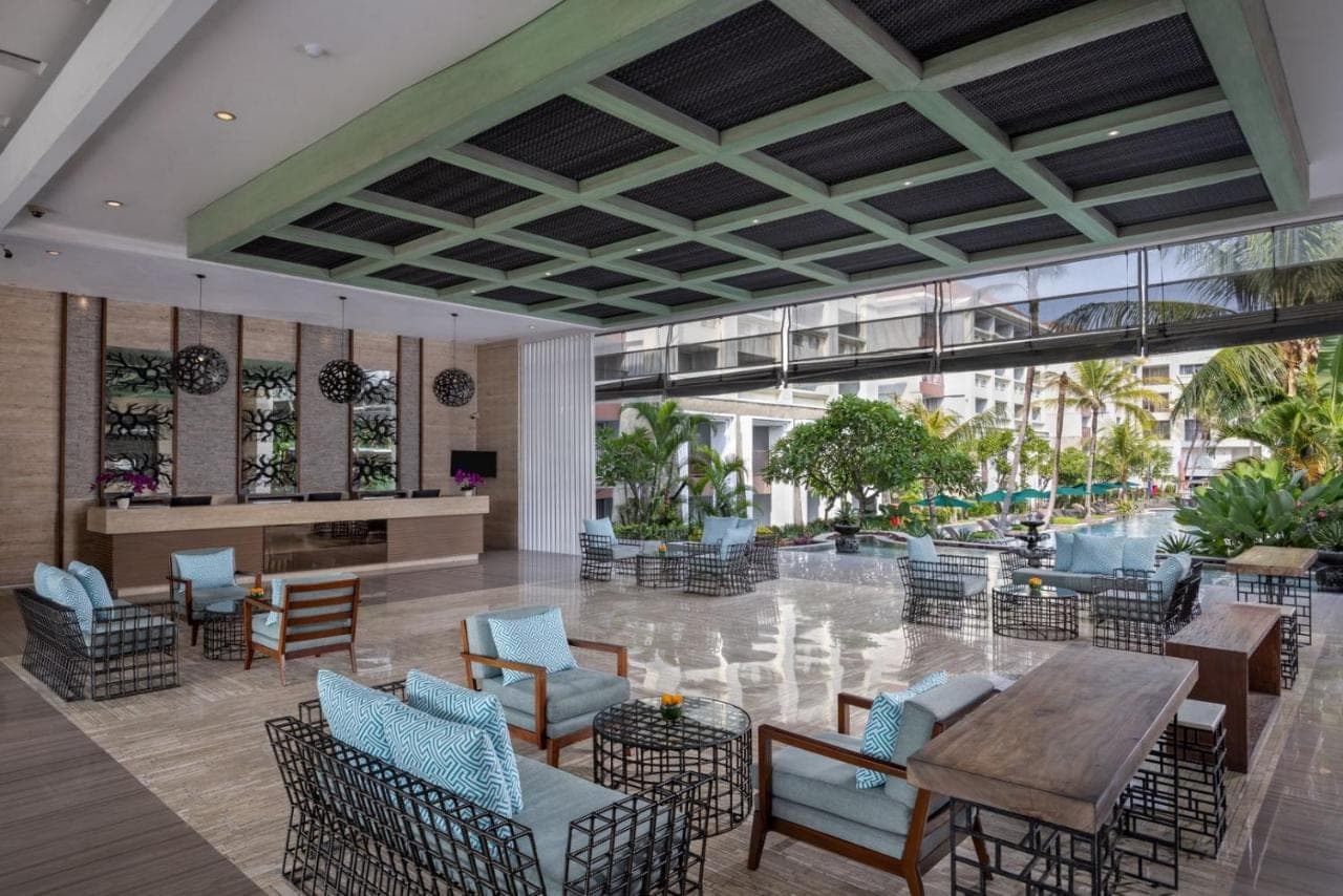 a lobby of a hotel with tables and chairs at Sanur Resort Watujimbar in Sanur