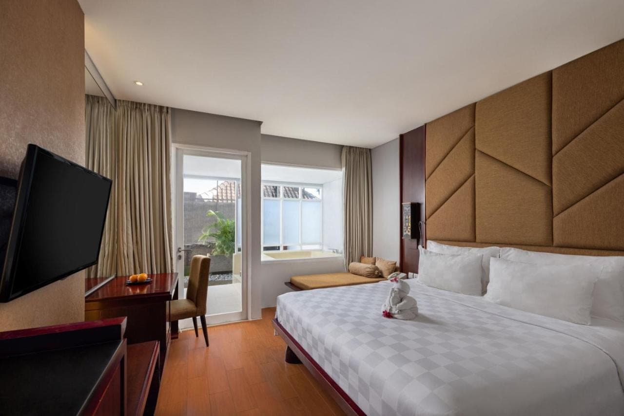 a hotel room with a bed and a television at Sanur Resort Watujimbar in Sanur