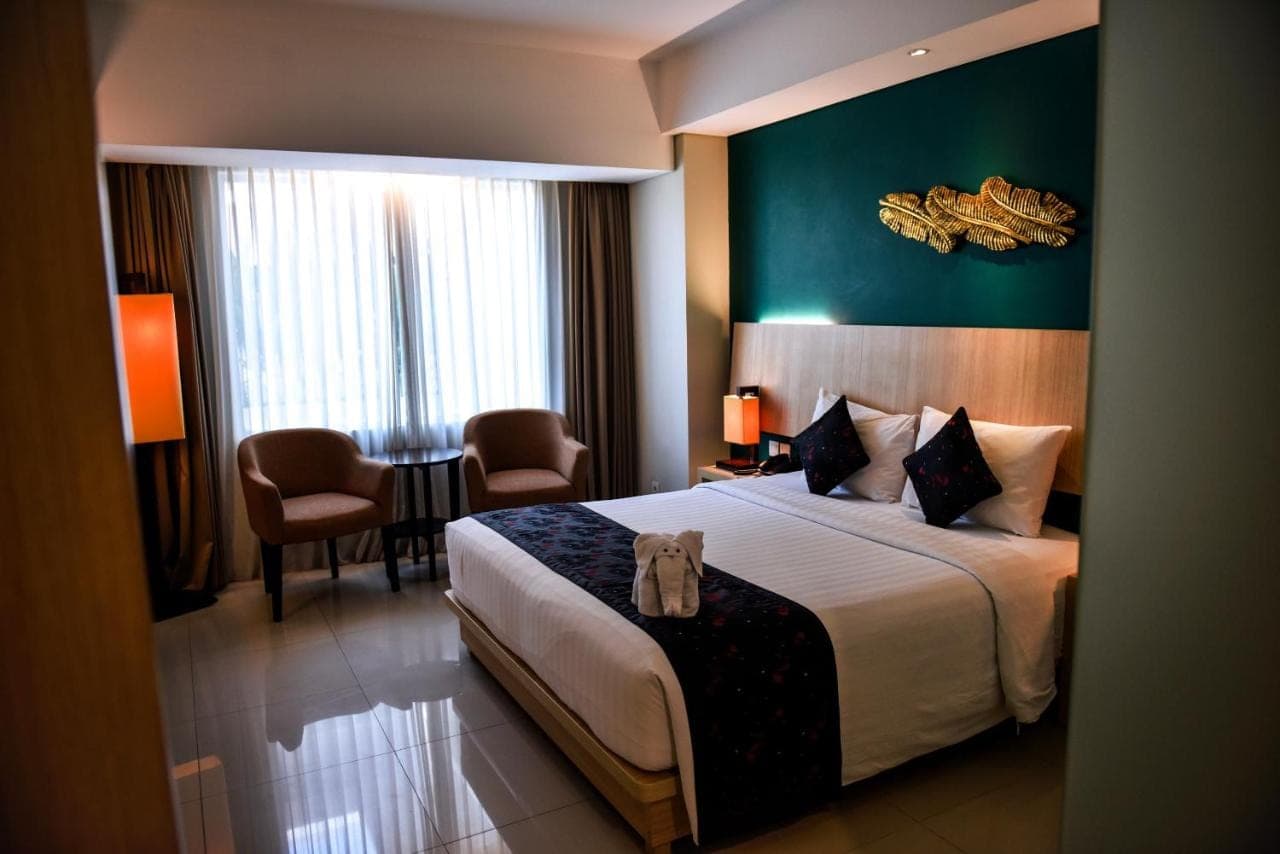 a hotel room with a bed and a table and chairs at The Kana Kuta Hotel in Kuta