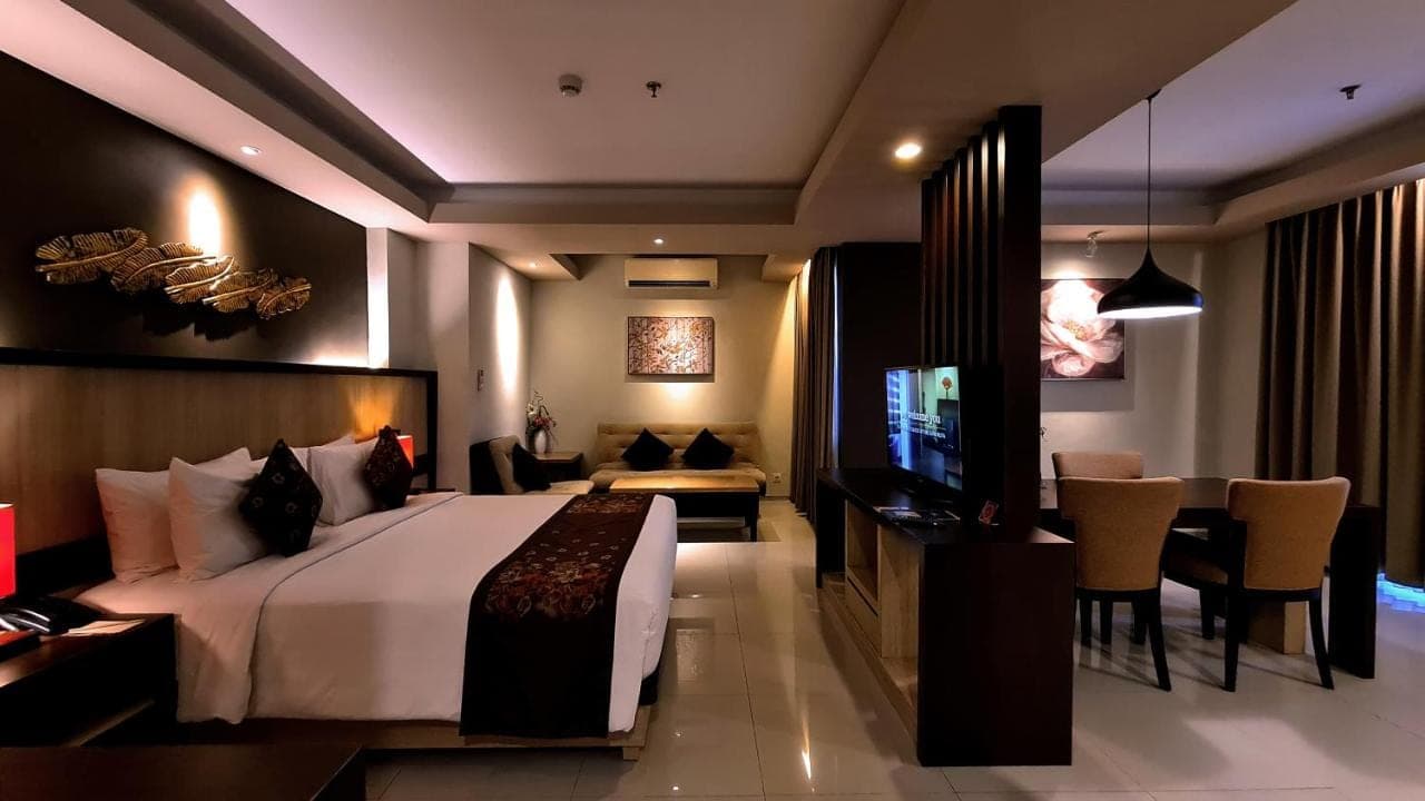 a hotel room with a bed and a television at The Kana Kuta Hotel in Kuta